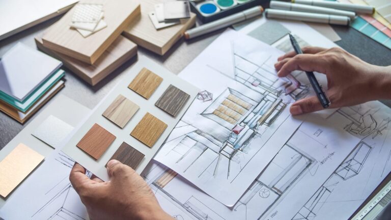 Mani che disegnano un progetto d’interni con campioni di legno