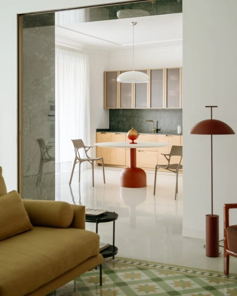 Zona pranzo con tavolo tondo bianco, sedie e lampada a sospensione vista dal soggiorno